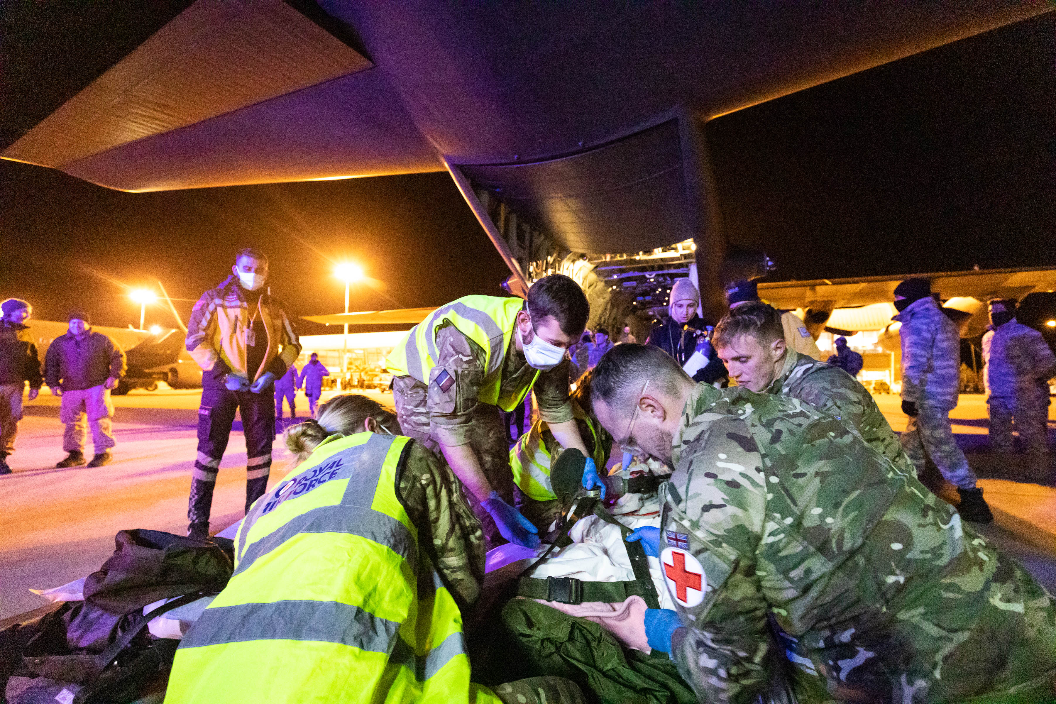 Image shows RAF medics attending patient on the airfield by RAF Hercules.